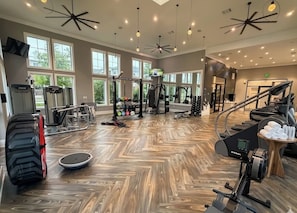 A spacious gym with various exercise equipment, large windows, and a herringbone wood floor. - Families favorite Luxury Suites + Saltwater Pool+Gym + Free Parking+Ev Charging (Matthews)