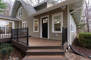 A two-story house with a front porch, a black front door, and a covered entryway. - Riverside Retreat Vacation Home (West Lafayette)