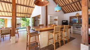 Uma cozinha espaçosa com uma ilha de madeira, banquetas e luminárias pendentes.