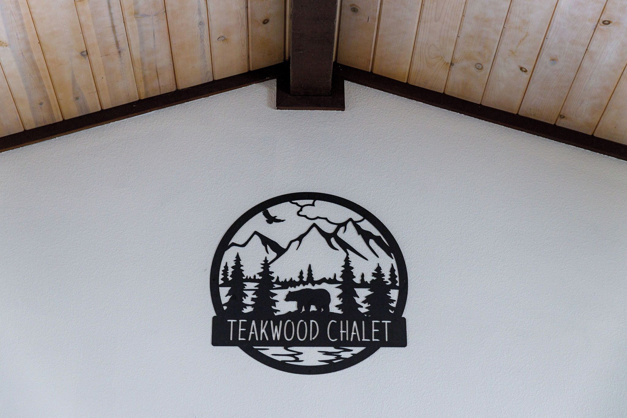 A logo with a bear, mountains, and trees on a white floor.