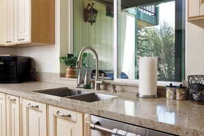 A kitchen with a double sink, stainless steel faucet, and a microwave. - Teakwood Chalet - Games / Fire Pit / Minutes to Lake and Ski (Big Bear Lake)