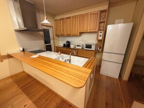 Eine moderne Küche mit Holzschränken, einem weißen Kühlschrank und einem Einbauofen.