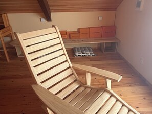 Ein Holzbstuhl in einem Raum mit Holzdielen, einer Bank und Louis Vuitton Kisten.