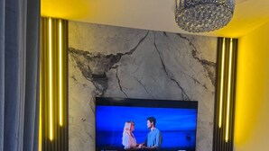 Un soggiorno moderno con una parete in marmo, un televisore a schermo piatto, un divano e un tavolino da caffè in vetro.