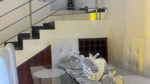 Un interno moderno con un tavolo da pranzo in vetro, una scala in metallo e una testiera imbottita.