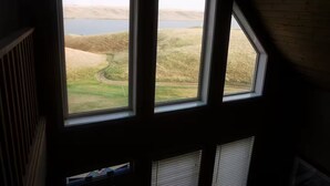 Ein Zimmer mit drei Fenstern, das Blick auf eine grüne Landschaft und ein Gewässer bietet.