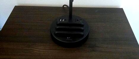 A wooden nightstand with a black lamp and a circular coaster with 'HG Hylton Hospitality Group' text.