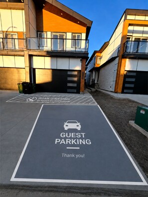 Un espace réservé au stationnement des visiteurs, avec un panneau indiquant « PARKING POUR LES VISITEURS » et le message « Merci ! ».