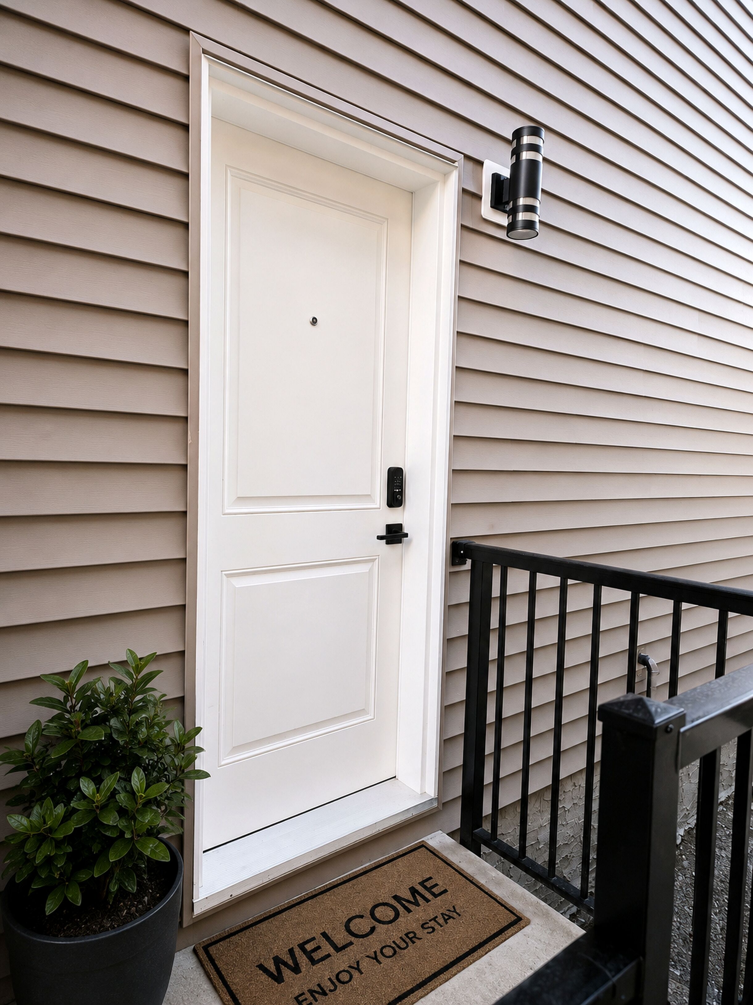 A white door with a doormat that reads 'WELCOME ENJOY YOUR STAY.'