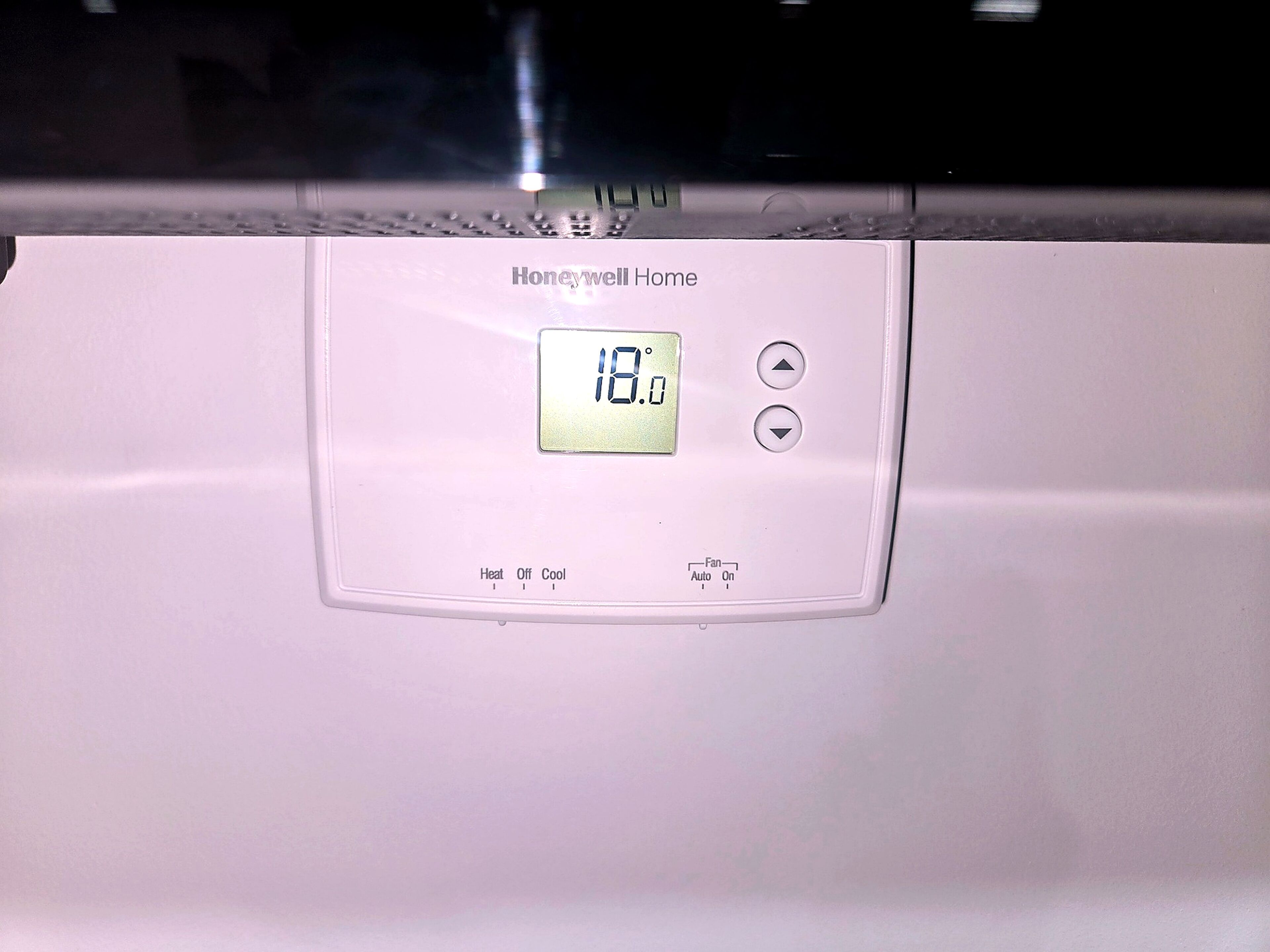 A Honeywell Home thermostat with a digital display reading 18.0 degrees Celsius, heat, fan, and auto settings.