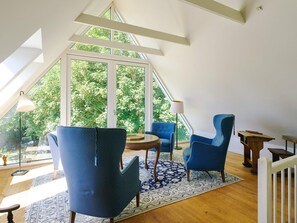 A room with a sloped ceiling, large windows, and blue upholstered chairs. - 4 Person Holiday Home in Sejero (Sejero)