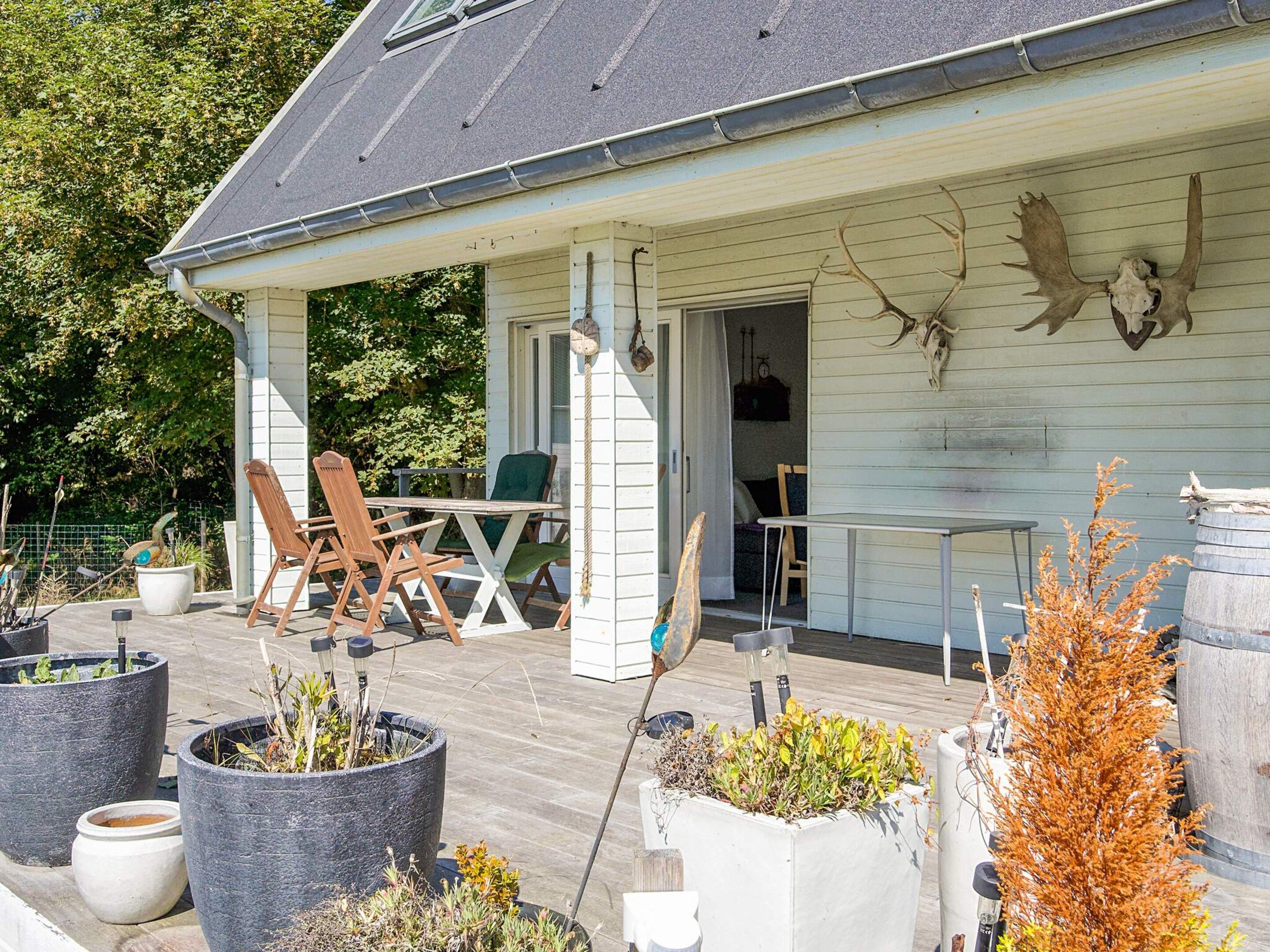 A covered porch with outdoor seating, potted plants, and a deer skull mounted on the wall.