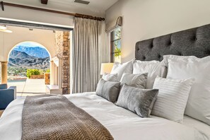 Ein Schlafzimmer mit einem großen Bett, Blick auf Berge und einer Terrasse mit Pool.