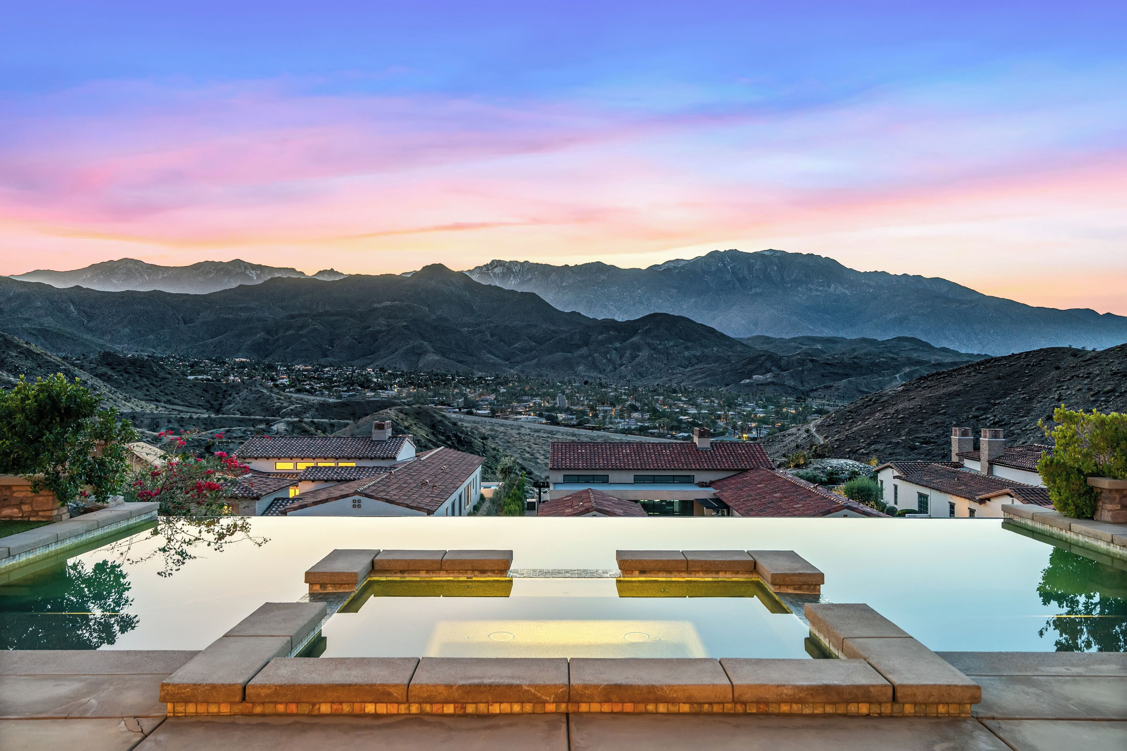 An infinity pool with a clear view of a mountain range and a town below.