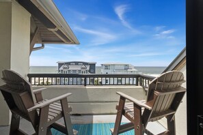 A balcony with two Adirondack chairs, a view of the ocean, and a building across the water. - The Club at Mexico Beach, 3BD/2BA, panoramic gulf views, steps to the beach, community pool! (Mexico Beach)