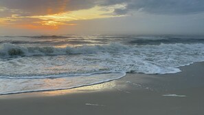 Una playa con olas y un atardecer.