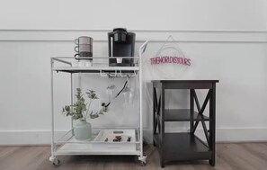 A white wall with a black coffee machine and a clear glass cart with a plant and glasses. -  Houston Heights 3 Beds + Garage (Houston)