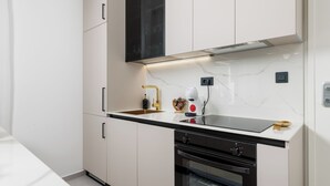 Una cocina moderna con armarios blancos, un horno negro y un lavamanos de acero inoxidable.