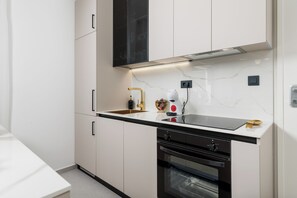 Eine moderne Küche mit weißen Schränken, einem schwarzen Backofen und einer Spüle aus Edelstahl.