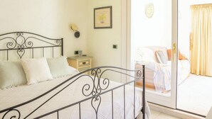 Een slaapkamer met een bed, nachtkastje en uitzicht op het balkon.