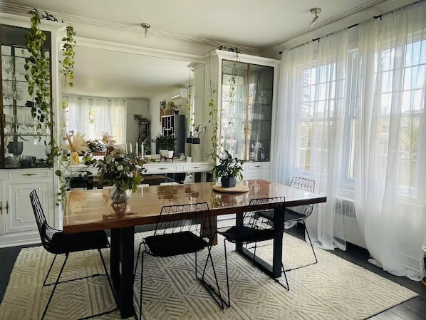 Un coin repas avec une table en bois, des chaises noires et un tapis Ă motifs.