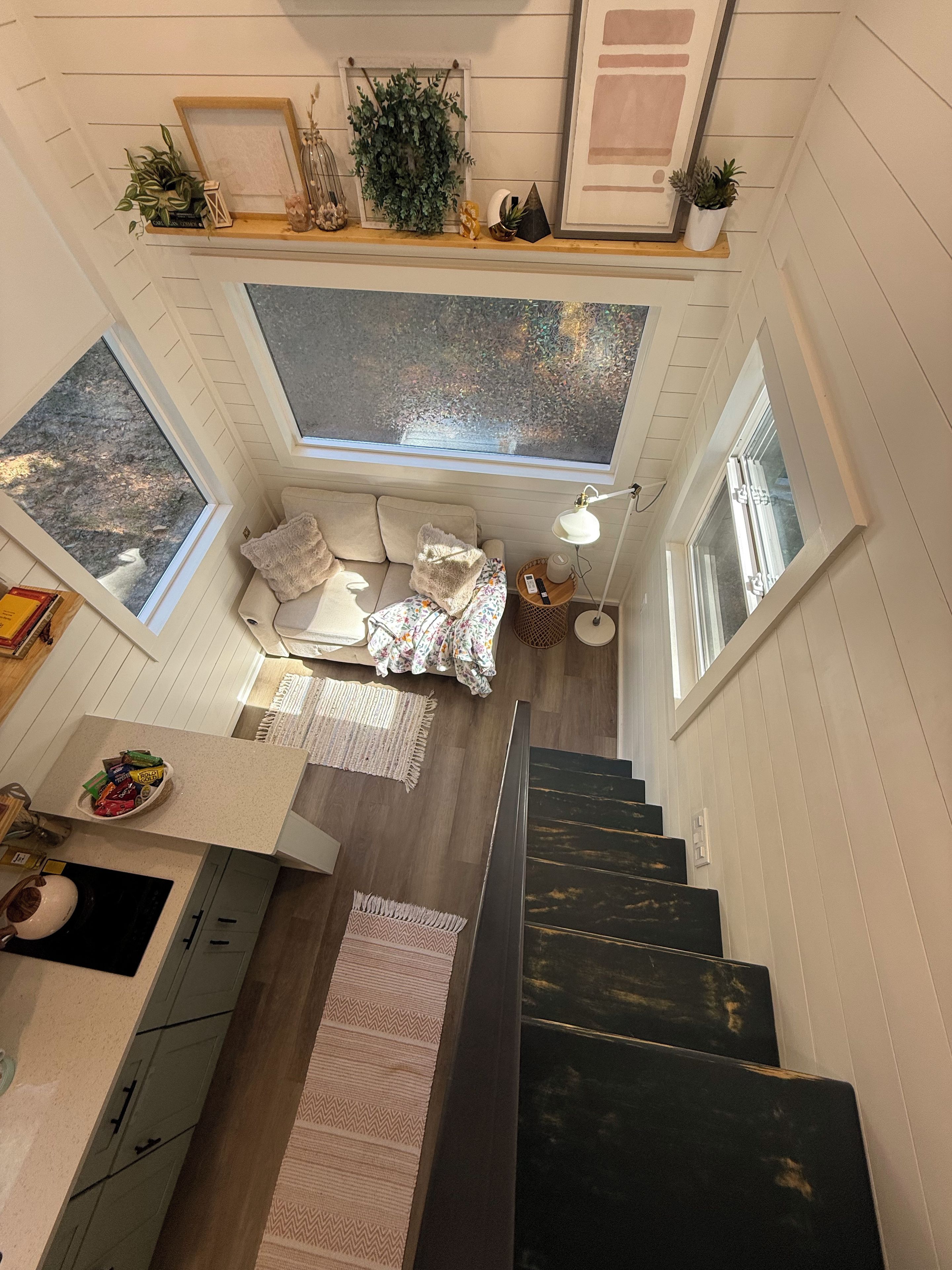 Ein gemütliches Interieur mit einer Treppe zu einem Schlafzimmer im oberen Bereich, einer Küchenzeile und einem Essbereich.