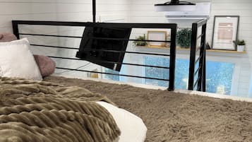 Et soveværelse med seng, hængekurv, loftventilator og udsigt til en pool.