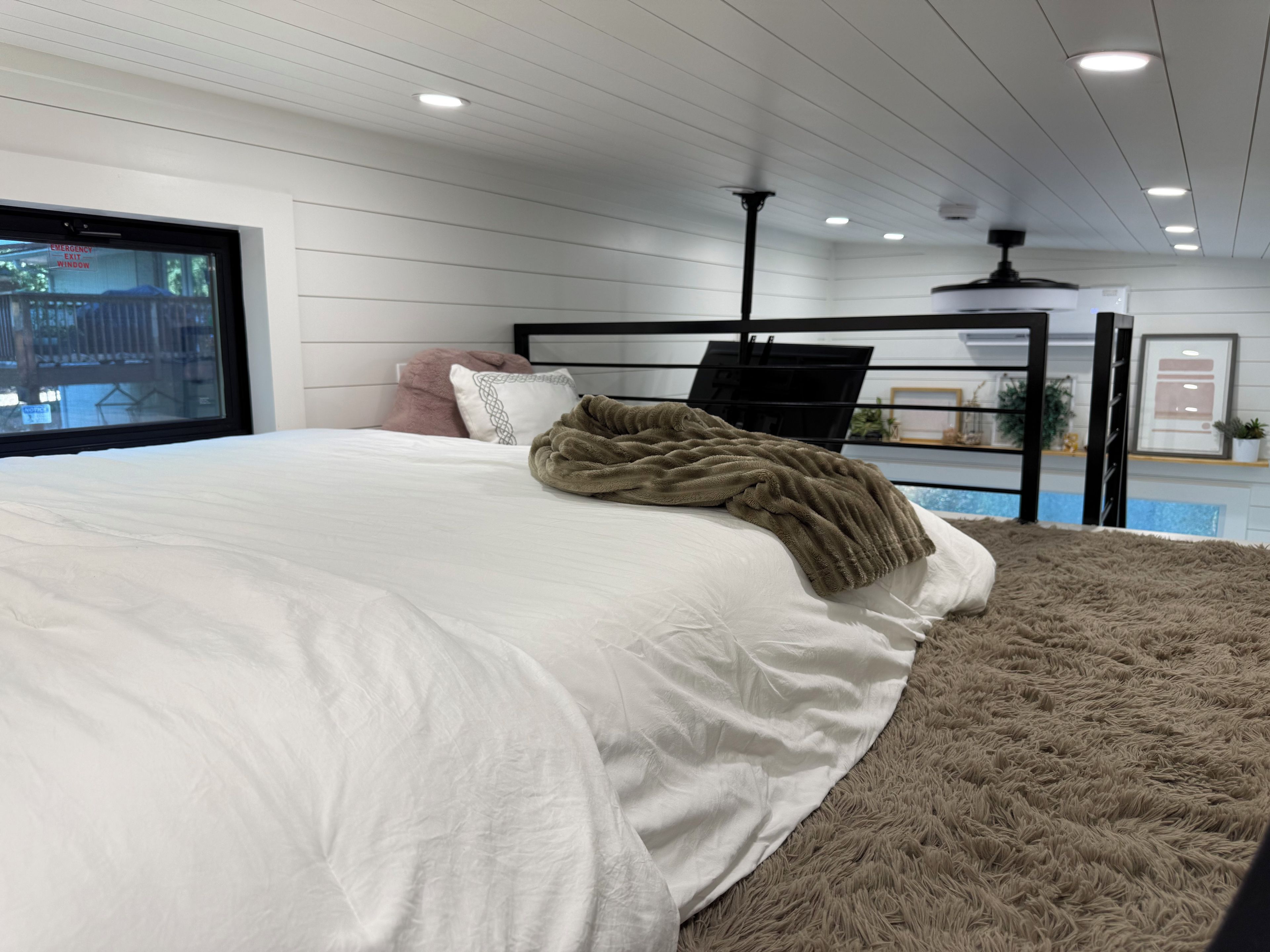 Ein Schlafzimmer mit einem Bett, einem Fenster und einem Deckenventilator.