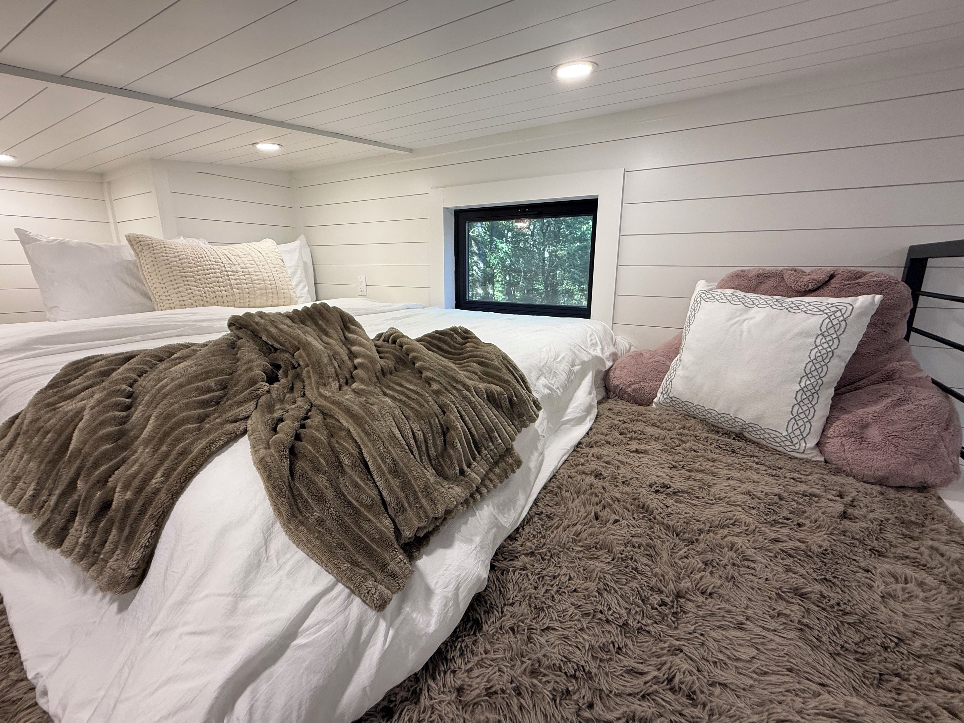 A bedroom with a bed, a window, and a view of trees.