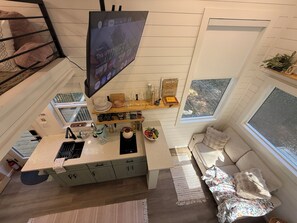 Una cucina compatta con isola centrale, una zona pranzo con divano e un'ampia finestra che offre vista all'esterno.