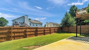 A backyard with a wooden fence, a concrete patio, and a house with a porch. - Newly Renovated Guest Floor (Mableton)