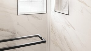 A bathroom with a glass shower enclosure, a towel rack, and a wall-mounted mirror. - Newly Renovated Guest Floor (Mableton)