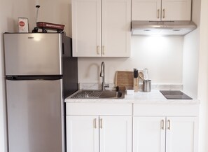 Eine moderne Küche mit einem Edelstahl-Kühlschrank, einer Spüle mit Wasserhahn, einem Schneidebrett und einem Messerblock.