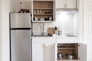 A kitchen with a stainless steel refrigerator, a wooden cutting board, and a sink.