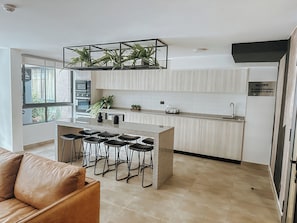 Eine moderne Küche mit einer zentralen Kochinsel, Barhocker, einer Mikrowelle und einem Kühlschrank.