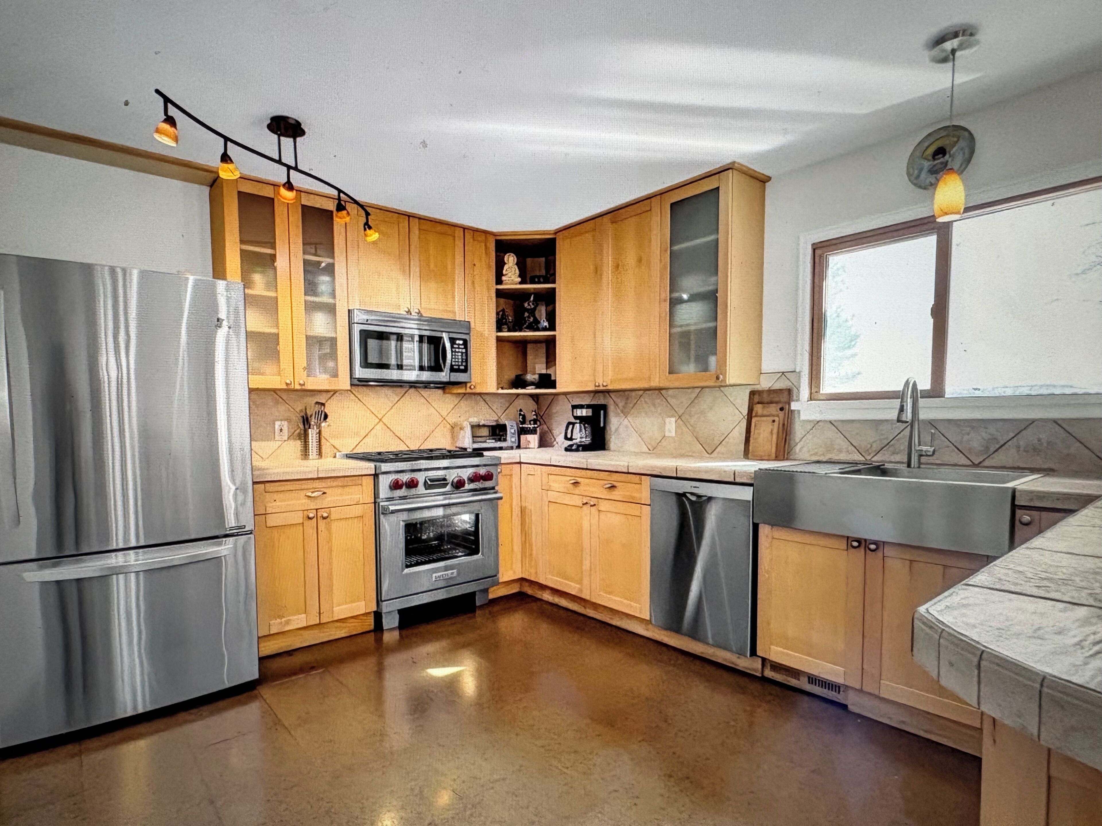A modern kitchen with stainless steel appliances, wooden cabinets, and a built-in oven.