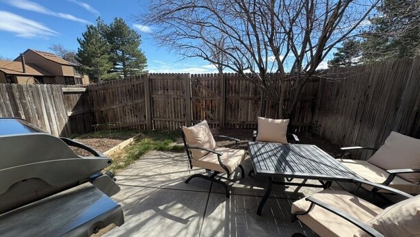 Eine Terrasse mit Grill, Gartenmöbeln und einem Holzzaun.