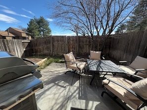 Eine Terrasse mit Grill, Gartenmöbeln und einem Holzzaun.