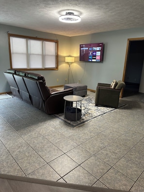 A living room with a sofa, a small table, a lamp, and a television mounted on the wall. - Edge of town unit 1, Comfortable 2 bedroom with queen beds, AC w covered porch (Wabash)