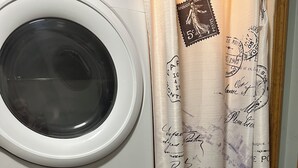 Een Samsung wasmachine met bedieningspaneel, een droger en een gordijn met tekst en stempels in vintage stijl.