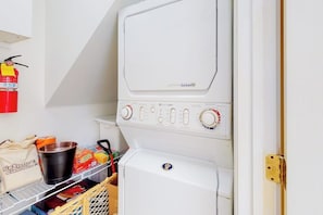 Ein Waschraum mit einer weißen Waschmaschine, einem Trockner und einem an der Wand befestigten Feuerlöscher.