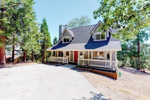 Ein zweistöckiges Haus mit Veranda, rotem Eingang und Auffahrt.