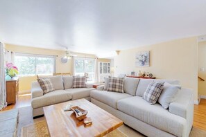 Ein Wohnzimmer mit einer Eckcouch, einem Holztisch und einem Essbereich mit Tisch und Stühlen.