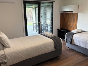 Et hotelværelse med to senge, en skydedør til et udendørs område, en trævæg og et lille bord.