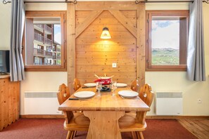 A wooden dining table with chairs, a central table lamp, and a view of a mountain landscape through a window. - Les Alpages du Corbier - A314 - Télésièges à 250 m (Villarembert)