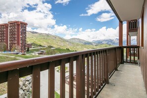A balcony with a view of a mountainous landscape, a tall building, and a traditional structure. - Les Alpages du Corbier - A314 - Télésièges à 250 m (Villarembert)