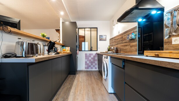Una cocina moderna con encimera de madera, electrodomésticos de acero inoxidable y lavadora integrada.