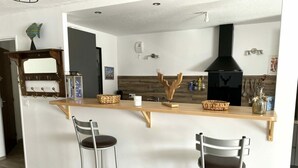 Una cocina con una isla de madera, dos taburetes de bar, una lámpara colgante y una campana extractora negra.