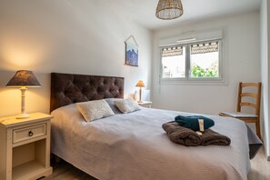 Ein Schlafzimmer mit einer gesteppten Kopfteil, einem Nachttisch mit Lampe, einem Fenster mit Blick und einem Sessel.