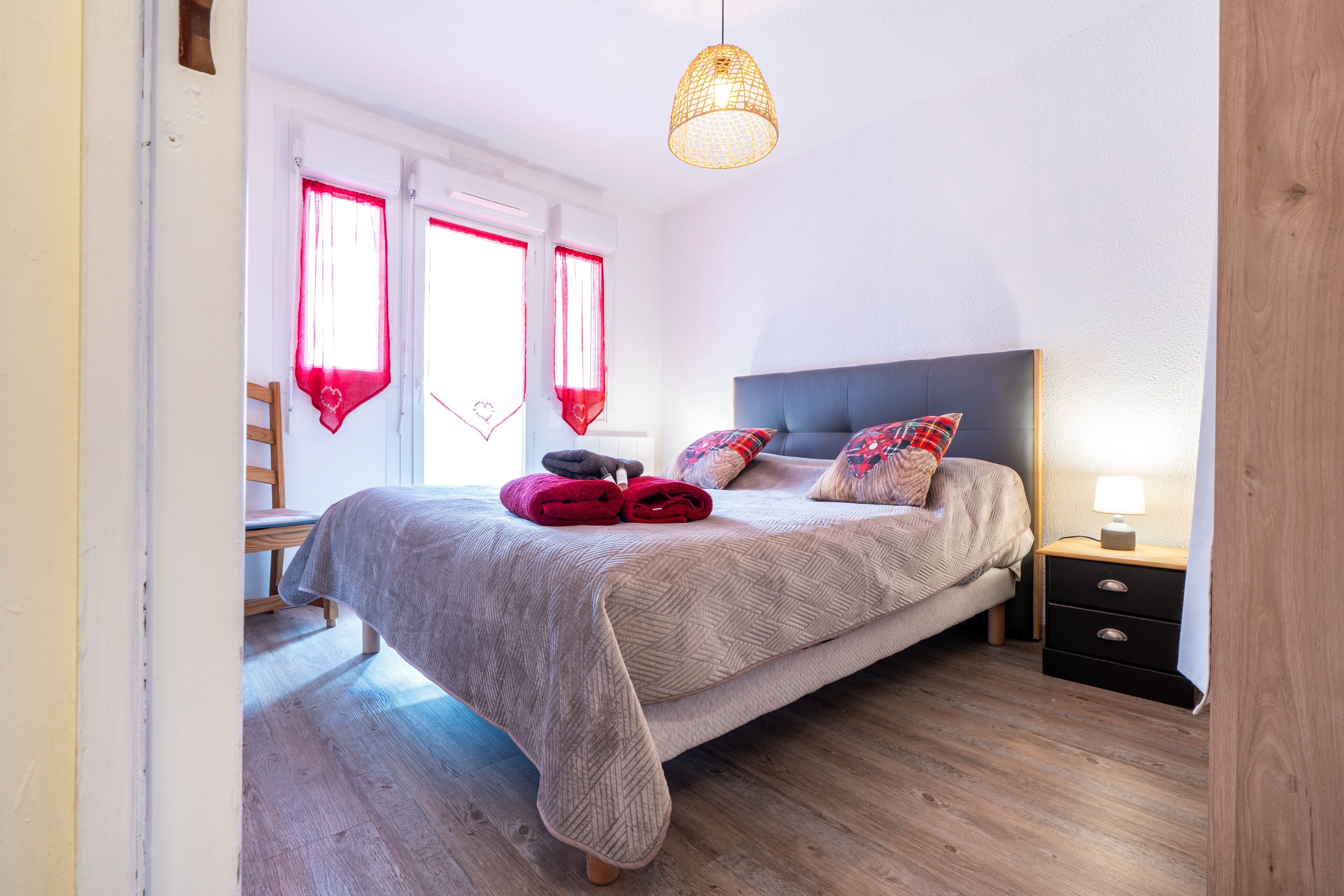 Une chambre à coucher avec un lit, une table de chevet, une lampe et une fenêtre avec des rideaux.
